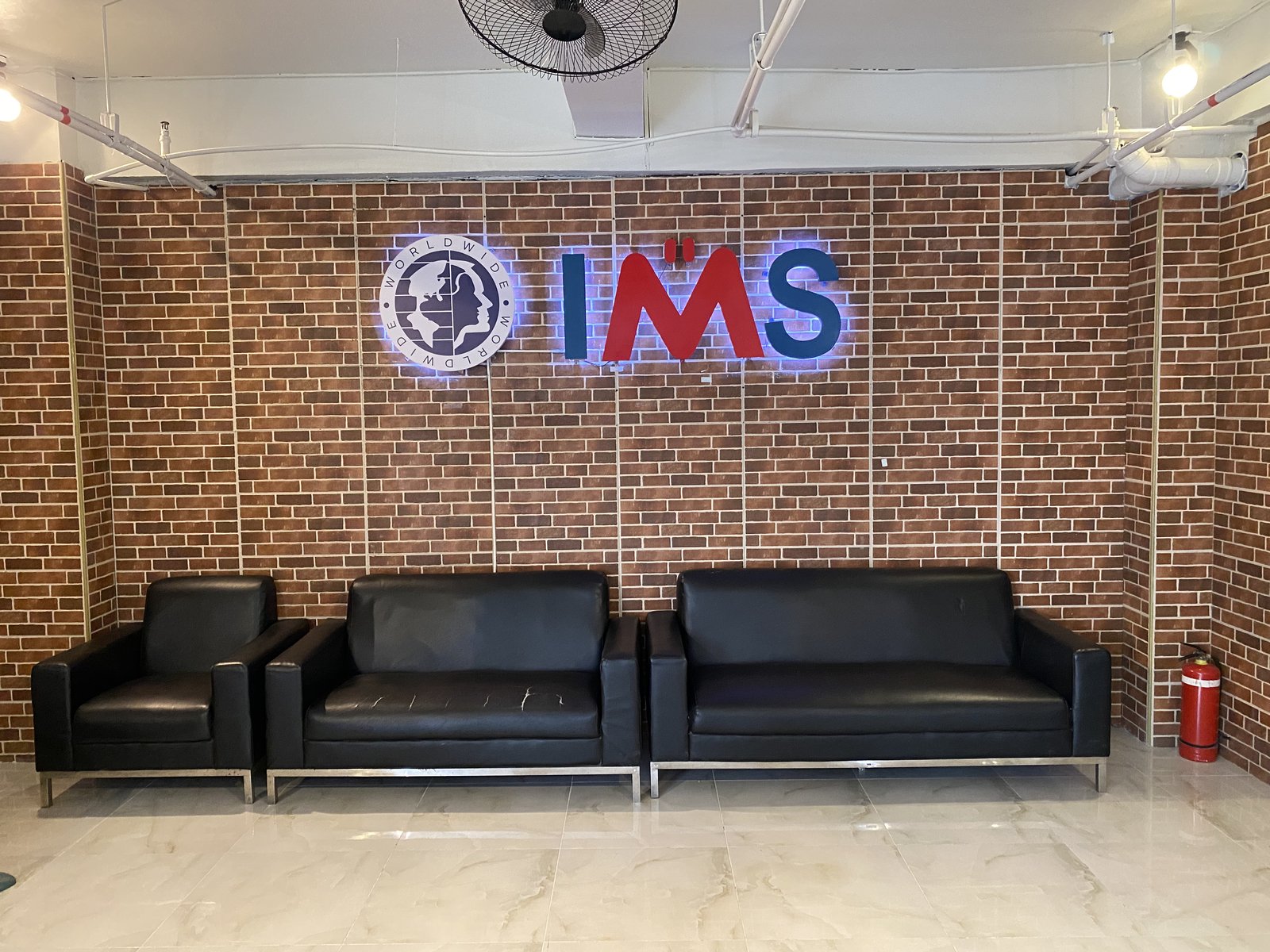 IMS Academyのエントランス。レンガ調の壁にIMSのロゴサイン、革張りのソファ