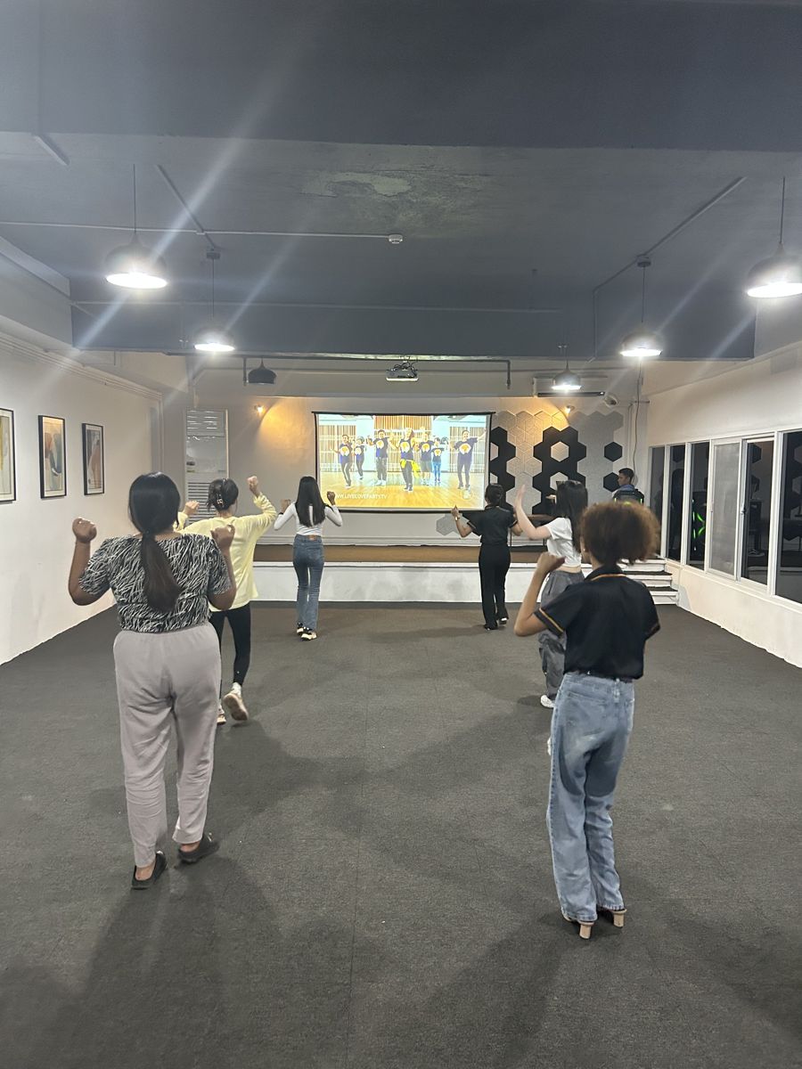 ホールでスクリーンの映像に合わせてズンバを踊る学生(後ろ姿)